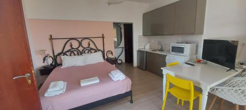 a bedroom with a bed and a table and a kitchen at Golden view apartments Myrina Limnos in Mirina