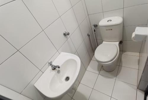 a white bathroom with a toilet and a sink at LM HomeyA 3 BdRm Coastline View condo for 4-14 Pax with Netflix & Coway Water Purifier in Tanjong Tokong