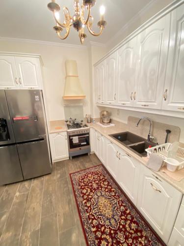 a kitchen with white cabinets and a stainless steel refrigerator at Υπέροχη οικογενειακή κατοικία στον Πειραιά, 3 λεπτά από μετρό in Piraeus