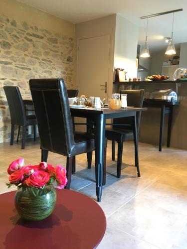 - une salle à manger avec une table, des chaises noires et des fleurs dans l'établissement Le Clos Pen Kear, à Plouarzel