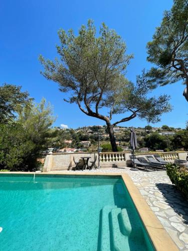 une piscine avec un arbre en arrière-plan dans l'établissement appartement bas de villa avec piscine privée partagée proche bord de mer, à Cagnes-sur-Mer