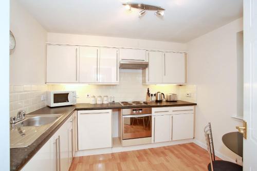a kitchen with white cabinets and a sink at Fonthill Apartments in Aberdeen