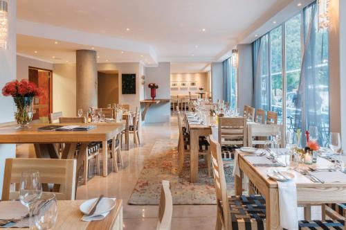 a restaurant with wooden tables and chairs and large windows at Cape Town Hollow Boutique Hotel in Cape Town