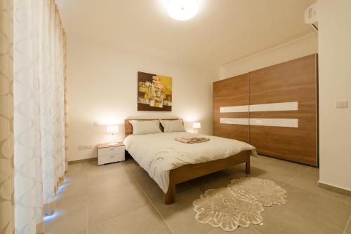 a bedroom with a large bed with a wooden headboard at Seafront Apartment Sliema in Sliema