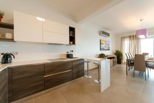 a kitchen with white cabinets and a dining room at Seafront Apartment Sliema in Sliema
