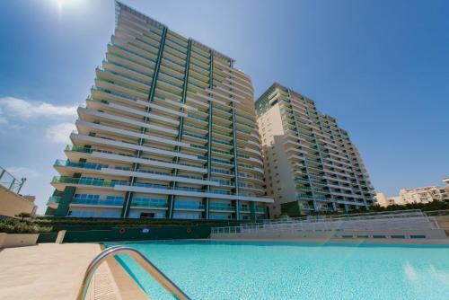 a large building with a swimming pool in front of it at Seafront Apartment Sliema in Sliema