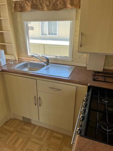 uma pequena cozinha com um lavatório e uma janela em 604 Seawick em Jaywick Sands