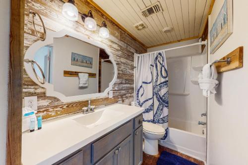 uma casa de banho com um lavatório, um WC e um espelho. em Kissing Palms em Panama City Beach