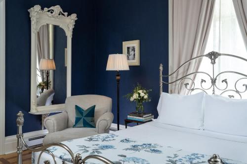 a bedroom with a bed and a chair and a mirror at Landmark Inn in Cooperstown