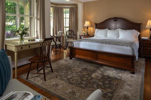 een slaapkamer met een bed en een bureau bij Landmark Inn in Cooperstown