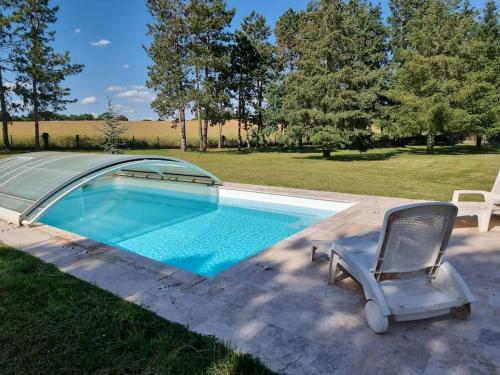 a chair and a swimming pool in a yard at Chambres Domaine de Saint Marc in Saint-Médard