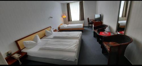 a hotel room with two beds and a television at Mansfelder Hof in Lutherstadt Eisleben