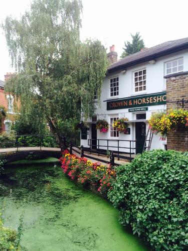 a river in front of a building with flowers at Holtwhites Hotel in Enfield