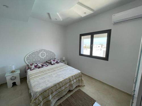 a white bedroom with a bed and a window at La casa blanca in Houmt Souk