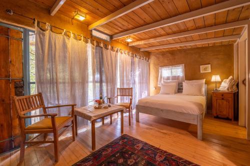 a bedroom with a bed and two chairs and a window at Hemdatya Stone Suites In The Galilee in Ilaniya