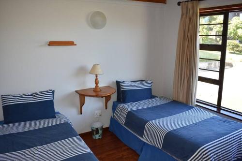 two beds in a room with a table and a window at PA Sands Beach House Kowie River 9 Sleeper Pool in Port Alfred