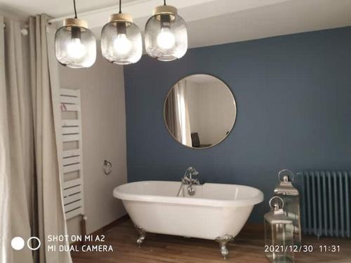 a bathroom with a white tub and a mirror at SAMANDINE HOME in Bayeux