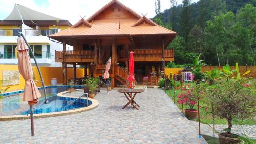 a resort with a pool and a table and umbrellas at Golden Teak Resort Baan Sapparot in Kamala Beach