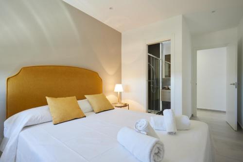 een witte slaapkamer met een groot wit bed met gele kussens bij Bright & Modern 2 Bedroom Apartment 300m to the Beach - Marbella in Marbella