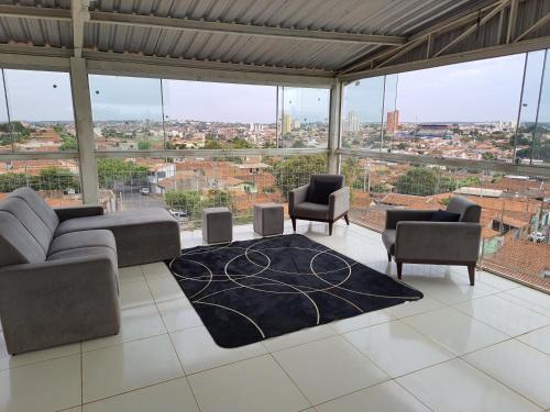 a living room with couches and chairs and a large window at Pousada Pimenta Olimpia in Olímpia