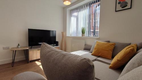 uma sala de estar com um sofá e uma televisão de ecrã plano em Treasured 1 Bedroom Jewellery Quarter Apartment em Birmingham