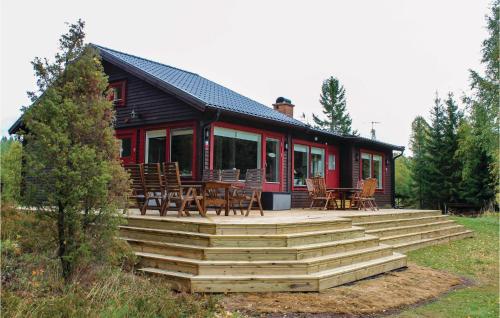 a log cabin with a deck and tables and chairs at Awesome Home In Älgarås With Wifi in Hallerud
