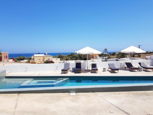 a swimming pool with lounge chairs and umbrellas at myLithos Suites in Monolithos
