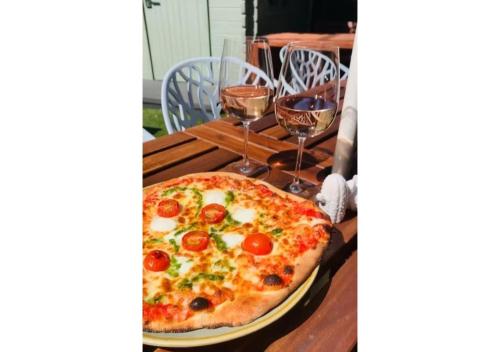 a pizza sitting on a table with two glasses of wine at Florence House Boutique Hotel and Restaurant in Portsmouth