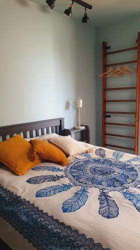 a bed with a blue and white blanket and orange pillows at Mareena_apartments in Liepāja