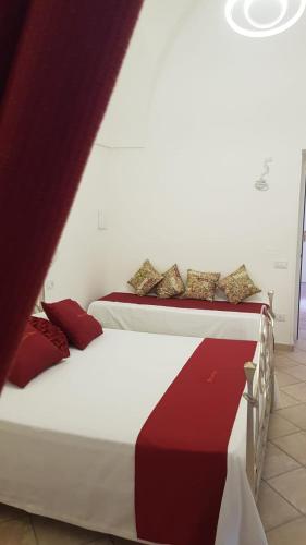 two beds in a room with red and white at Casal Duca in Taranto