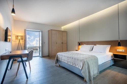Armantanis Luxury Suites في أريوبوليس: غرفة نوم بسرير وطاولة ومكتب