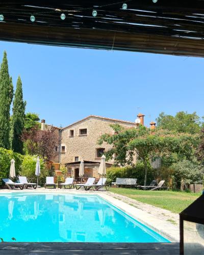a swimming pool in a yard with chairs and umbrellas at La Lolita ( Adults Only ) in Sant Martí Vell