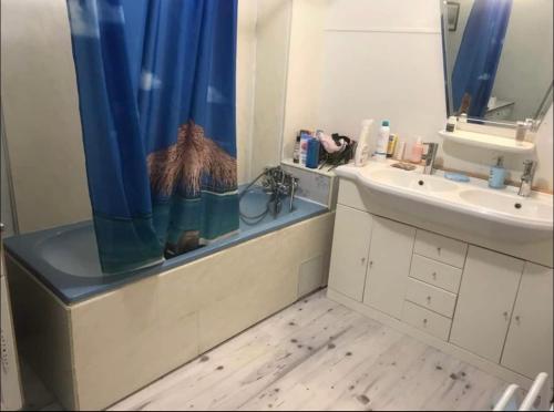 a bathroom with a sink and a blue shower curtain at Treacy’s résidence in Morez