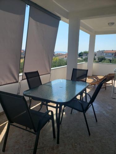 a glass table and chairs on a patio at Apartmani Čiklić in Dobropoljana