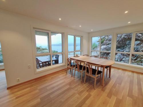 a dining room with a table and chairs and windows at Ropeid Villa Fjordferie in Ropeid