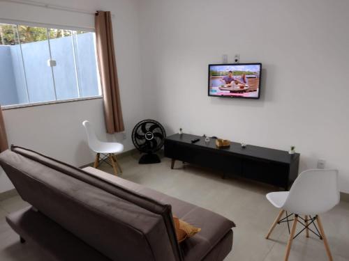 a living room with a couch and a tv on a wall at Casa Premium em Bonito - Linda e Confortável in Bonito