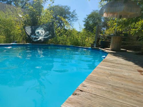 uma grande piscina azul com um deque de madeira em La Cabane des Trappeurs em Crépy-en-Valois