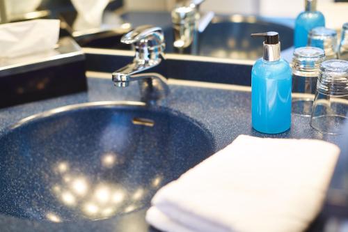 un lavabo con una botella de jabón azul. en Ko´Ono Hotel, en Constanza