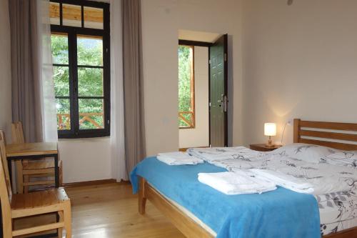 a bedroom with a bed with blue sheets and a window at Guesthouse Mountain View in Mestia