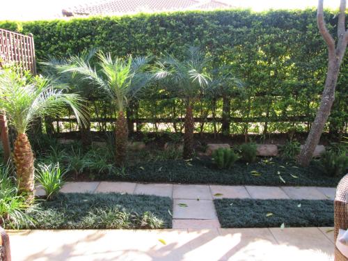 a fence with palm trees in a garden at Schneiders Boutique Hotel in White River