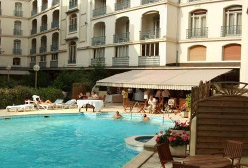 a swimming pool in front of a large building at Hôtel Aletti Palace in Vichy