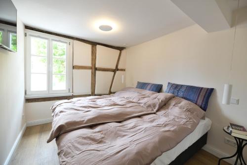 Cette chambre comprend un grand lit et une fenêtre. dans l'établissement Das schiefe Haus Wohnung Festspiele, à Heppenheim