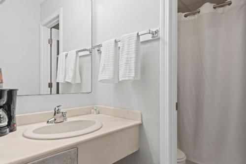 Baño blanco con lavabo y espejo en The Niantic Inn en Niantic