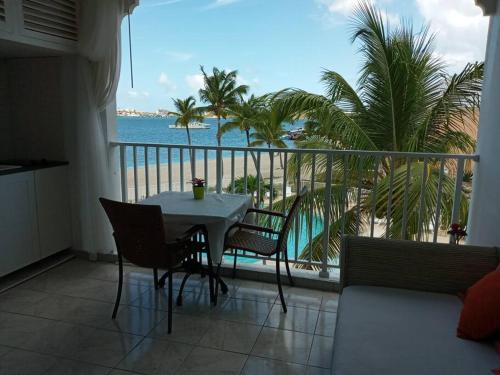 a table and chairs on a balcony with a view of the ocean at Just in paradise in Baie Nettle