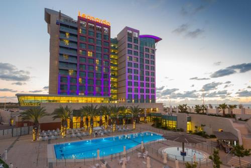 um hotel com piscina em frente a um edifício em Leonardo Plaza Ashdod em Ashdod