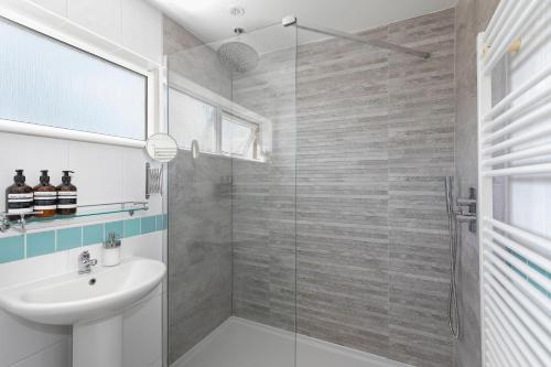 a bathroom with a sink and a glass shower at Parkside House in Stevenage