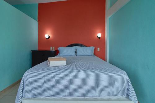 ein Schlafzimmer mit einem weißen Bett und einer roten Wand in der Unterkunft Los Angeles en el Paraiso in San Patricio - Melaque
