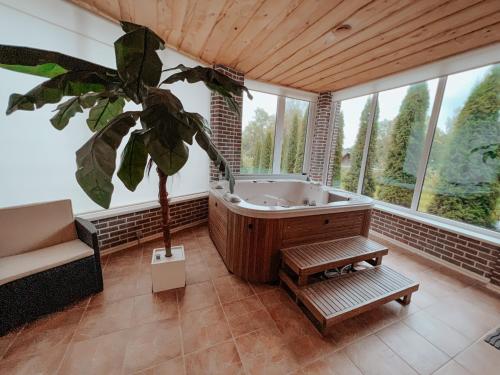 Tõrva的住宿－Near the lake apartment with hot tub and sauna，带浴缸和植物的大浴室