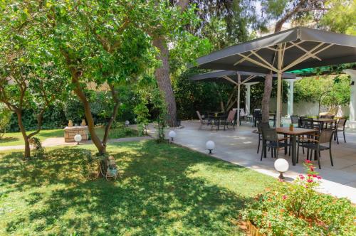 un patio con mesas y sillas bajo una sombrilla grande en Acropol Hotel en Atenas