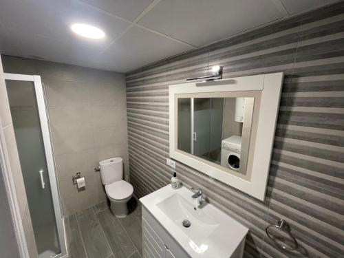 een badkamer met een toilet, een wastafel en een spiegel bij Nuevo Azorin I in Conil de la Frontera